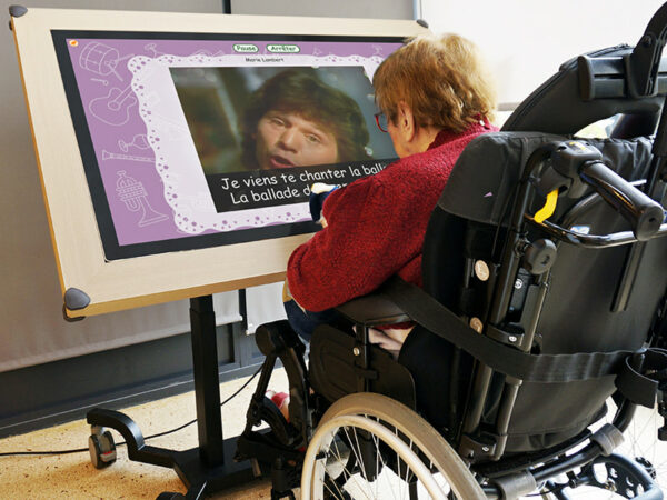 Une personne en fauteuil roulant utilise une table tactile interactive inclinée.
